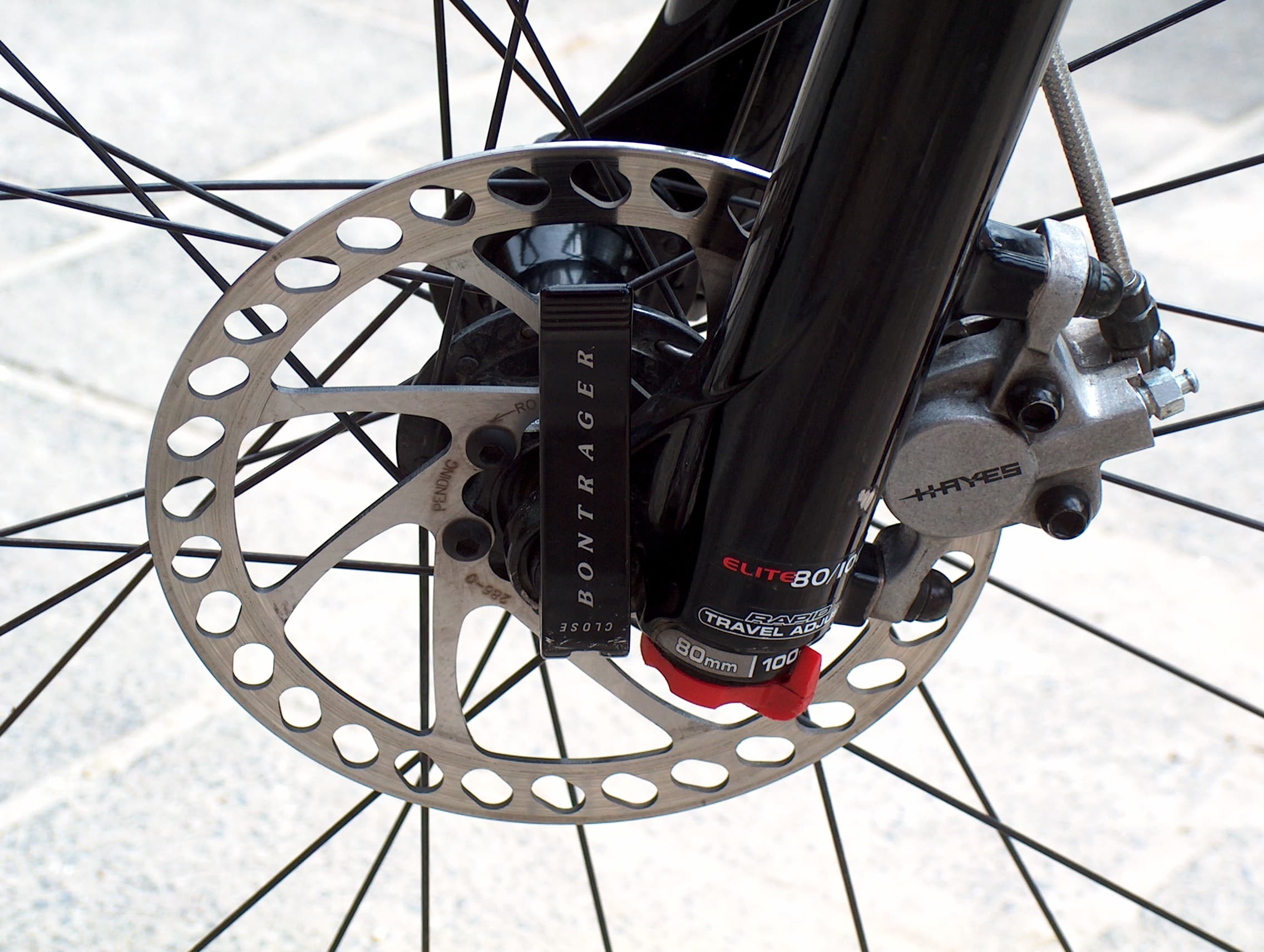A real hydraulic bicycle disc-brake caliper, hose and rotor installed at a front wheel