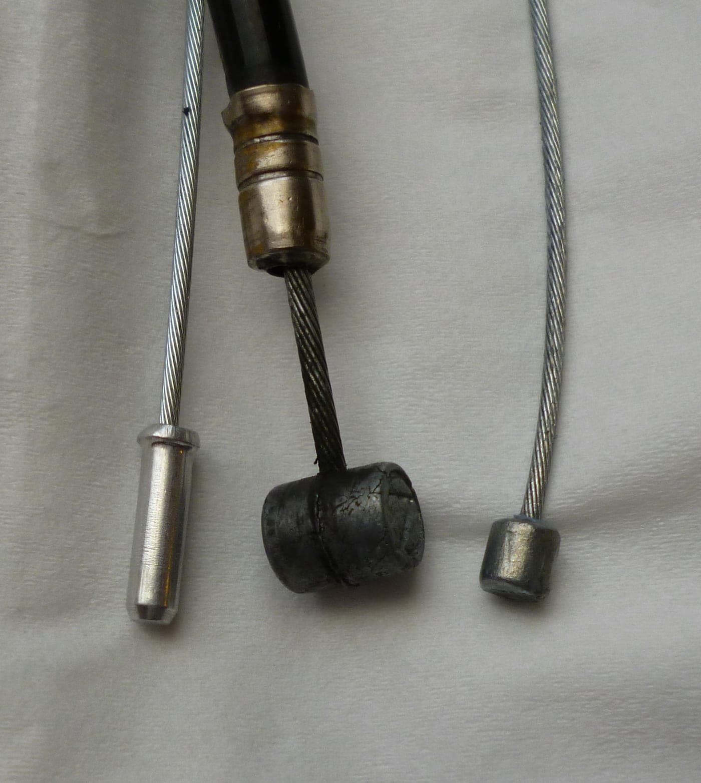 Three bicycle cable endings including a brake cable in housing and a shift cable end