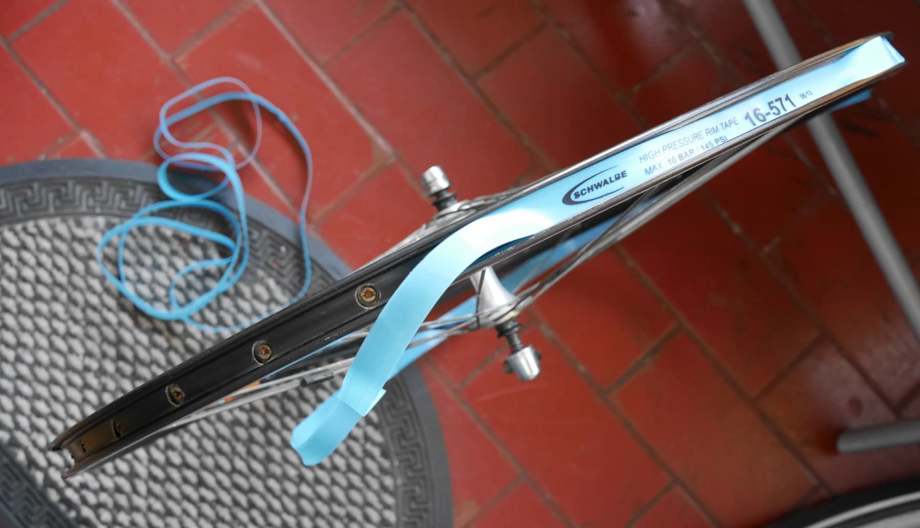 Blue rim tape being fitted into the bed of a bicycle rim