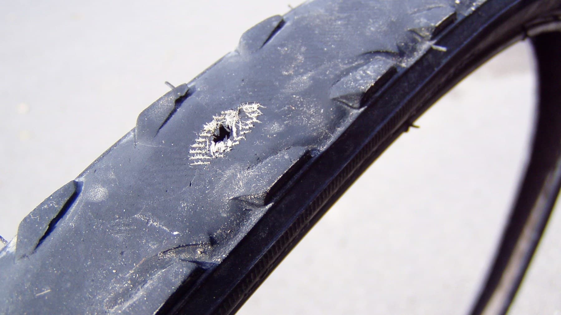 A bicycle tire worn through to visible casing threads