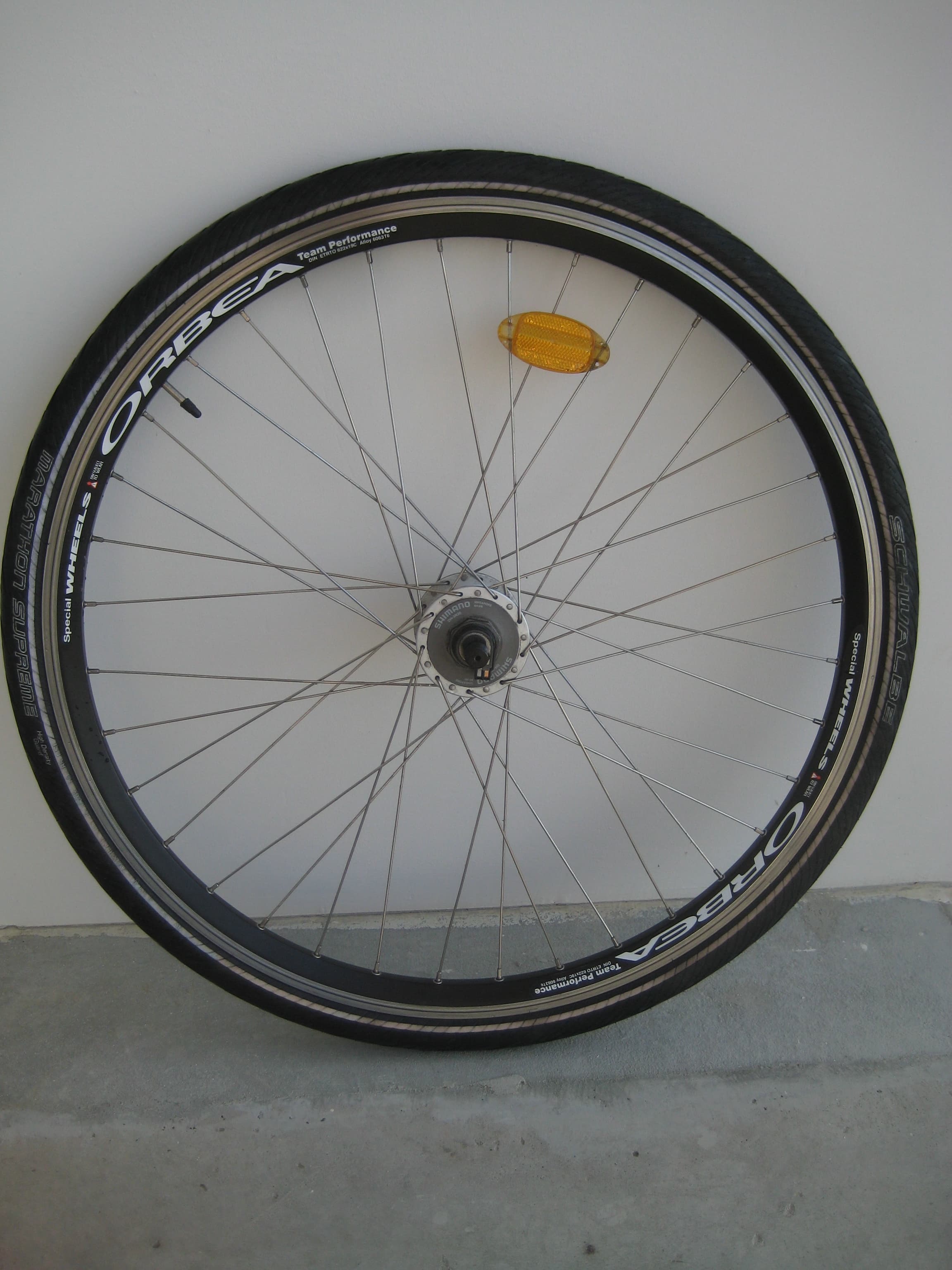 A loose trekking bicycle front wheel with a tire, rim-brake track, spokes, reflector, Schrader valve and dynamo hub